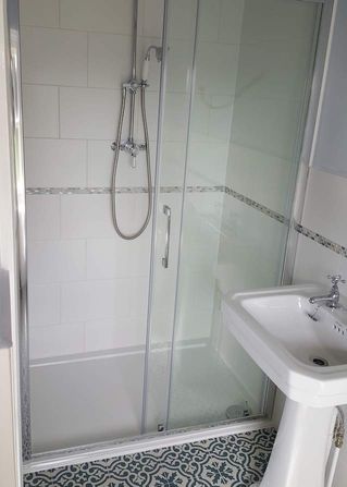 A traditional shower room, with a silver shower, and with a white wash basin